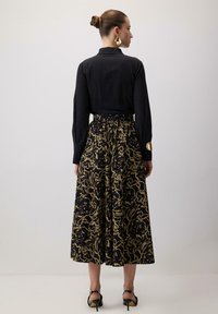 �Črn dolg rokav s ovratnikom v kombinaciji z dolžino krila do tal, ki ima zlat cvetlični vzorec na črni podlagi. Črne petke.