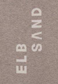 Dicker, strukturierter Stoff in sanftem Taubengrau mit kräftigen, weißen Buchstaben, die "ELB SAND" vertikal und horizontal schreiben.