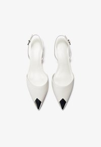 Biele slingback päty s špicatými špičkami, čiernymi špicatými akcentmi, hladkým koženým povrchom a úzkym remienkom na členku so striebornou prackou.