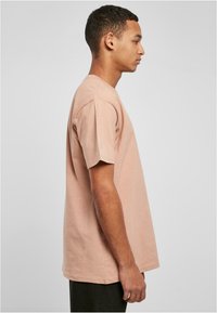 Lyserosa bomullstrøye med korte ermer, rund hals og rett snitt. Minimalistisk design, myk tekstur og ingen synlige mønstre.