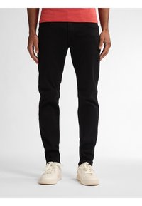 Zwarte katoenen jeans met een slim fit, voorzien van voorzakken en een strak ontwerp, gecombineerd met lichtgekleurde sneakers.