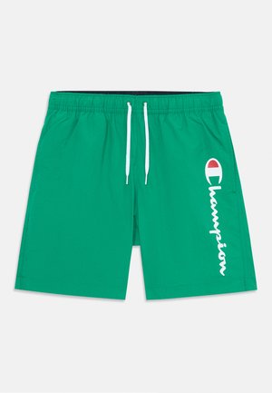 Pantaloni da bagno verdi realizzati in tessuto leggero, con vita elastica e cordino e un logo "Champion" bianco sul lato.