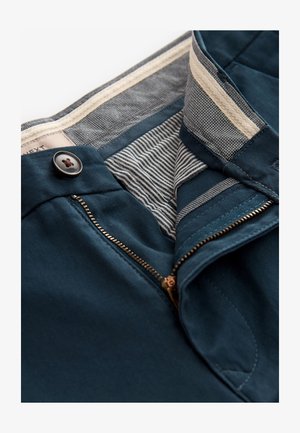 Mørkegrønne bukser med lynlås og knaplukning. Indersiden har stribet og mønstret for. Glat stof med skræddersyet pasform.