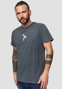 Grijze katoenen T-shirt met ronde hals, voorzien van een cartoonkarakterprint in wit, lichtblauw en bruin op de borst.