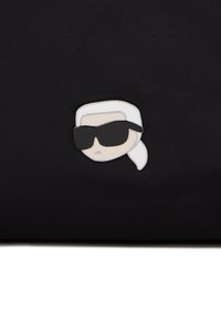 Enamel lapel pin depicting a stylized head with white hair and black sunglasses on a textured black background.