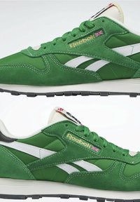 Zelené a bílé tenisky Reebok se semišovými a látkovými panely, zlatým logem s vlajkou Velké Británie, bílými středními podrážkami a černými gumovými podrážkami, zobrazené ze stran.