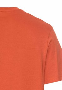 Korte mouwen T-shirt in feloranje katoen. Heeft een ronde hals en een gladde textuur met minimale stikdetails op de mouwen.