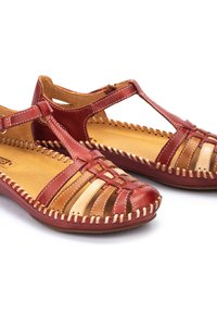 Sandalias de cuero rojas y beige con un diseño trenzado, que presentan una tira en T y acentos de costura. Plantillas de cuero suaves y suelas planas.