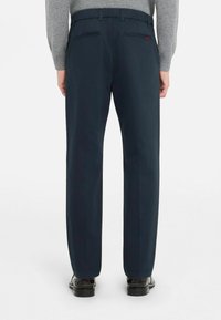 Pantalon habillé bleu marine avec devant plat, coupe droite et taille élastique. Comprend deux poches arrière et un marquage discret.