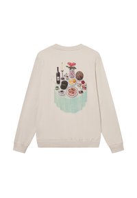 Μπεζ φούτερ με πολύχρωμο γραφικό τραπεζιού που περιλαμβάνει ένα μπουκάλι κρασί, λουλούδια και διάφορα εδέσματα σε ριγ έ τραπεζομάντιλο.