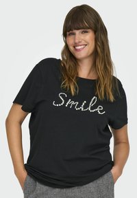 Juoda marškinėliai trumpomis rankovėmis, priekyje su žodžiu "Šypsena" dekoratyviniu perlų tipo dizainu. Minkšta medžiaga, laisvas fasonas.