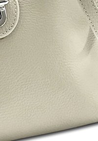 Beige Handtasche aus Kunstleder mit strukturiertem Oberflächen, silberner Hardware und runder Silhouette. Sie verfügt über einen Knopfverschluss und sichtbare Nähte.