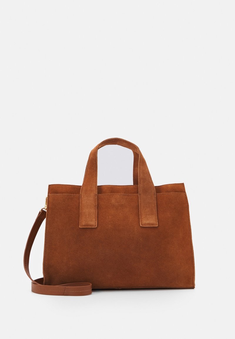 Sac fourre-tout en daim marron avec deux poignées supérieures et une bandoulière amovible. Présente une forme rectangulaire simple et une texture lisse.