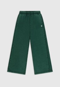 Groene wijde broek met een elastische tailleband, gemaakt van een gladde stof. Heeft een klein logo aan de linkerkant.
