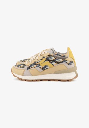 Paire de baskets beiges et jaunes avec des panneaux en tissu à motifs et des lacets blancs, présentée sur fond blanc.