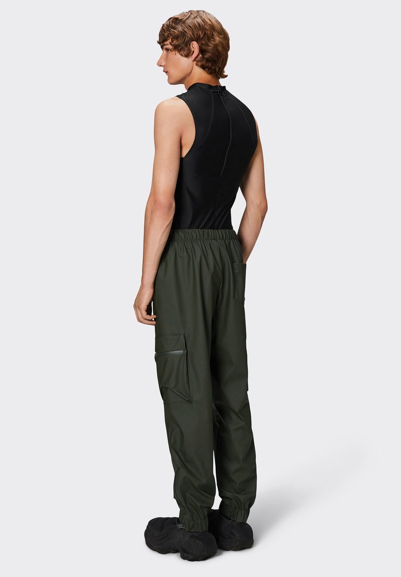 top nero senza maniche abbinato a pantaloni cargo larghi verde oliva con vita elastica, tasche laterali e calzature nere testurizzate.