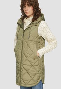 Gemusterte ärmellose Weste in Olivgrün, mit Kapuze, diagonalen Nähten, zwei Fronttaschen und einem Reißverschluss.