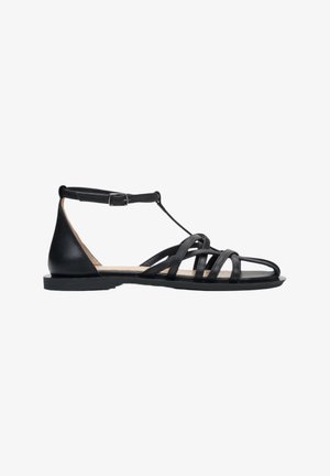 Schwarze Ledersandalen mit mehreren Riemen, einem Knöchelriemen mit Schnalle und einer flachen Sohle. Glatte Textur mit einem minimalistischen Design.