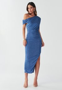 Modrá off-shoulder šaty s drapovaným telom, s riasením a s rozparkom po stehná, vyrobené z hladkej, elastickej tkaniny.