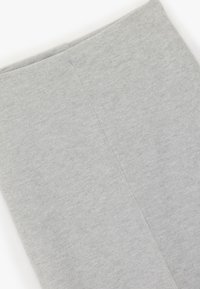 Harmaat, pehmeät leggingit, joissa on sileä rakenne. Ne ovat yksinkertaisessa designissa ilman näkyviä kuvioita tai kiinnityksiä.