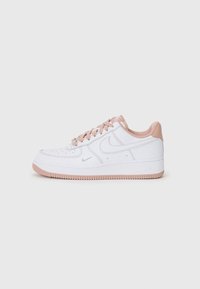 White leather sneakers with pink accents, round toe, perforated toe box, flat laces, and rubber outsole featuring a textured traction pattern.
