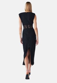 Robe midi en dentelle noire à manches courtes, taille en dentelle découpée et fente arrière. Texture lisse et silhouette élégante.