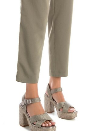 Sandalias de cuña beige con tiras de tejido grueso, que cuentan con un robusto tacón cuadrado. La plataforma tiene un acabado natural y texturizado.