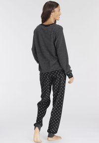 Black and white striped long-sleeve top paired with black pants featuring small white heart patterns. Material appears soft and comfortable.