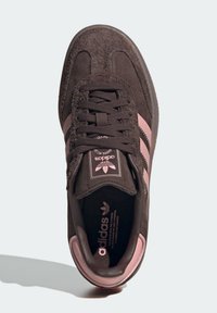 Dark brown Adidas sneaker with textured upper and pink stripes, viewed from above on a light background.