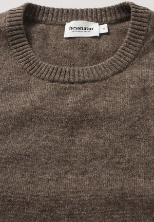 Brauner Wollpullover mit ribbeligem Rundhalsausschnitt und weicher Textur. Das Etikett trägt die Aufschrift "hessnatur" und die Größe "M." Einheitliches Strickmuster über das gesamte Stück.