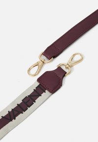 Curea din piele burgundy cu clips din metal cu ton de aur și țesătură crem cu textul "VALENTINO" în negru. Suprafață durabilă și texturată.