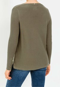 Olive'owy sweter z długimi rękawami i teksturowanym wykończeniem. Posiada okrągły dekolt i boczne rozcięcia u dołu. Tył ma mały metalowy akcent.