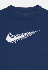 Tume sinine crewneck särk, millel on rindkere kohal suur valge Nike'i swoosh logo, millel on sakilised servad.