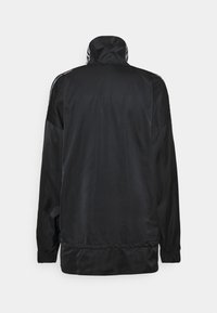 Černá sportovní bunda s vysokým límcem, dlouhými rukávy, elastickými manžetami a hladkou strukturou; má kontrastní pruhy podél ramen.