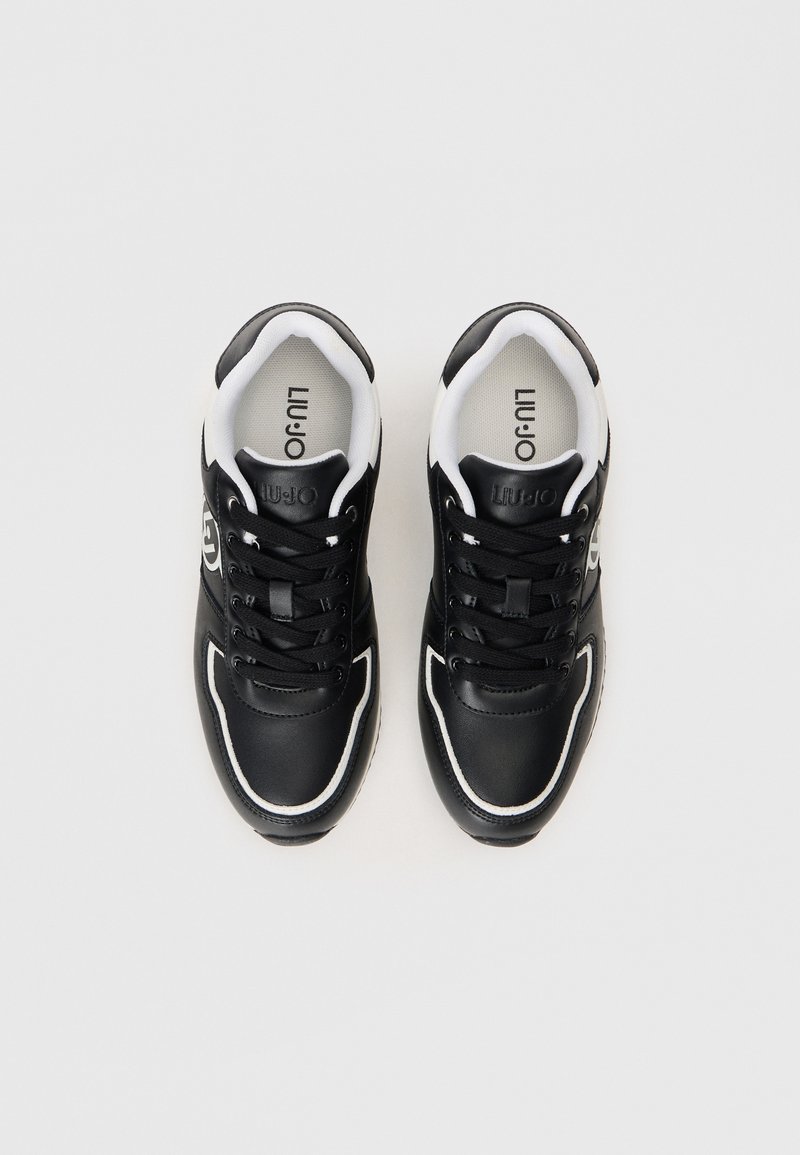 Zapatillas negras con acentos blancos, material de cuero, puntera redonda, diseño plano con cordones, con detalle del logo en el costado y cuello acolchado.