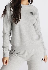 Grijze trui met ronde hals, geribbelde manchetten en zoom. Voorzien van een zwart geborduurd logo op de borst. Zachte, gestructureerde stof.