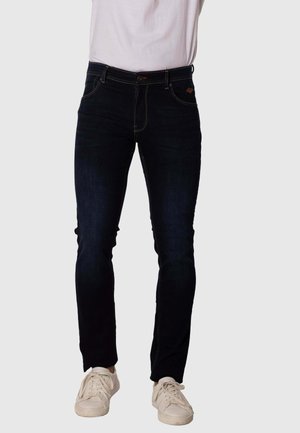 Jeans de denim azul oscuro con un corte slim, costuras amarillas en contraste, diseño de cinco bolsillos y cierre de botón en la cintura.