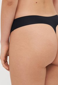 Black bikini bottoms with a smooth texture, minimal coverage, and a seamless design, featuring a soft, wide waistband.