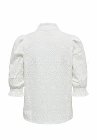 Blouse en dentelle blanche avec manches trois-quarts bouffantes, col à volants et motif floral ajouré complexe.