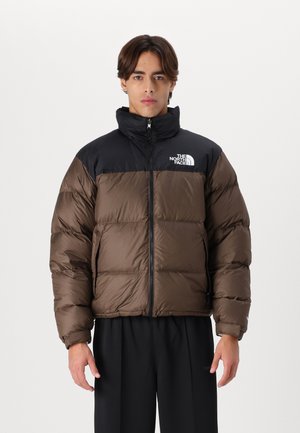 Chaqueta de plumón marrón y negra con un alto cuello, que presenta un cierre de cremallera en la parte frontal y el logo de North Face en el pecho. La tela tiene una textura brillante.