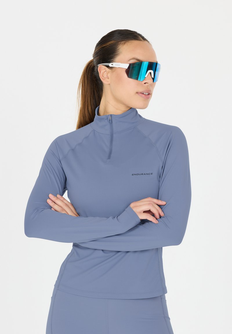 Lichtblauw sportshirt met lange mouwen en een half-rits kraag, met een gladde textuur en een zwart "ENDURANCE" logo op de borst.