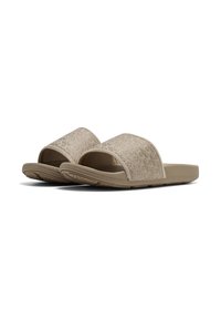 Beige slide sandals with a textured fabric upper and wide straps. Flat rubber sole features a patterned grip for traction.