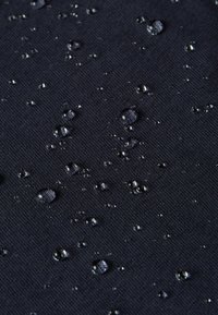 Waterdichte zwarte stof met een gestructureerd oppervlak, met verspreide druppels die de waterdichte eigenschappen benadrukken.