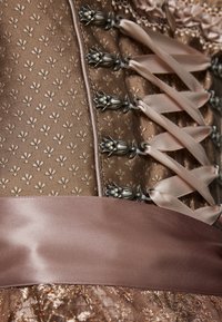 Brown satin corset featuring floral patterns, metallic hardware, and satin ribbons laced through eyelets, with a contrasting smooth waistband.