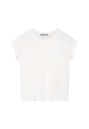 Un mannequin porte de grandes lunettes de soleil noires, un T-shirt blanc, un jean bleu ample et des chaussures marron sur un fond gris uni.