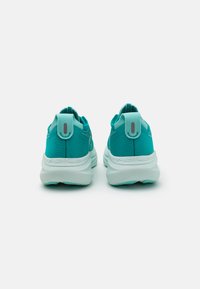 Turquoise athletic shoes with a textured fabric upper, padded collar, and a contrasting white sole. Features a pull tab and branding detail.