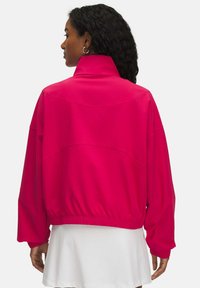 Chaqueta rosa, oversized, con un alto cuello, dobladillo elástico y mangas anchas, que presenta una textura suave y detalles de costura en la parte trasera.