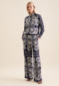 Set a fantasia navy con camicia colletto e pantaloni palazzo, realizzati in tessuto morbido con motivi paisley bianchi e dettagli.