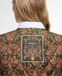 Gequilte groene jas met oranje bloemmotieven, voorzien van een label met "Barbour FARM RIO" en ingewikkelde borduursels, waaronder katten en bloemen.