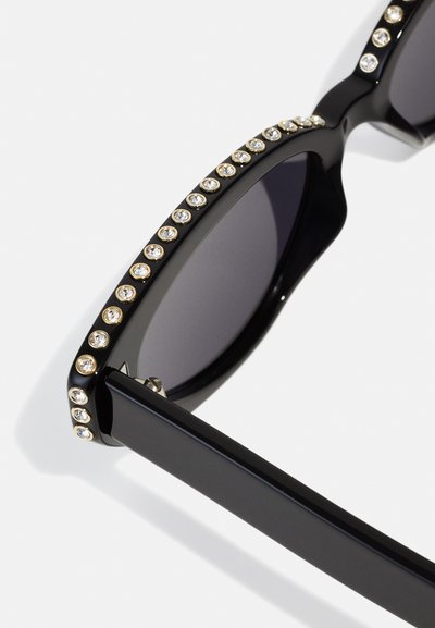 Black sunglasses with rectangular frames, embellished with circular clear rhinestones along the top edge. Dark lenses and sleek arms.